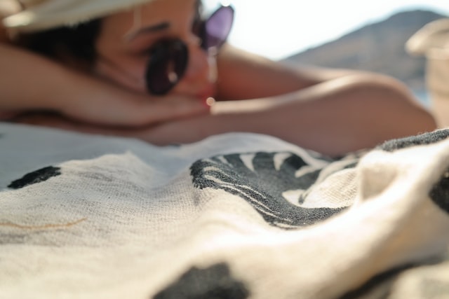 mujer relajándose en la playa con una toalla