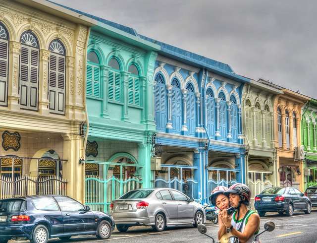 Pareja en un scooter fuera de casas luminosas en Tailandia