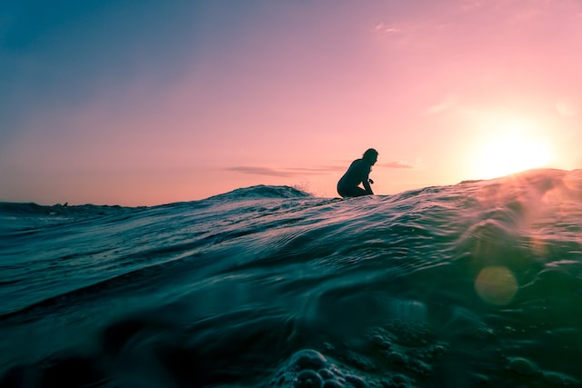 Persona sentada en una tabla de surf en aguas onduladas