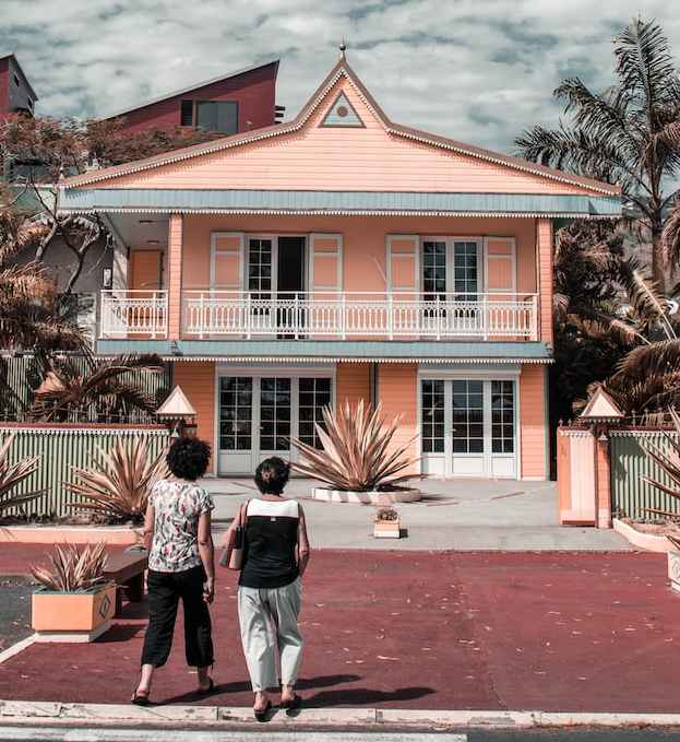 dos mujeres frente a una gran casa rosa