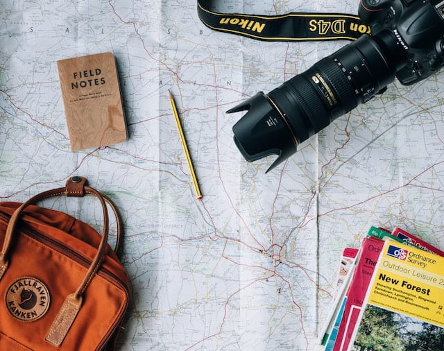 mapa con cámara, cuaderno y mochila