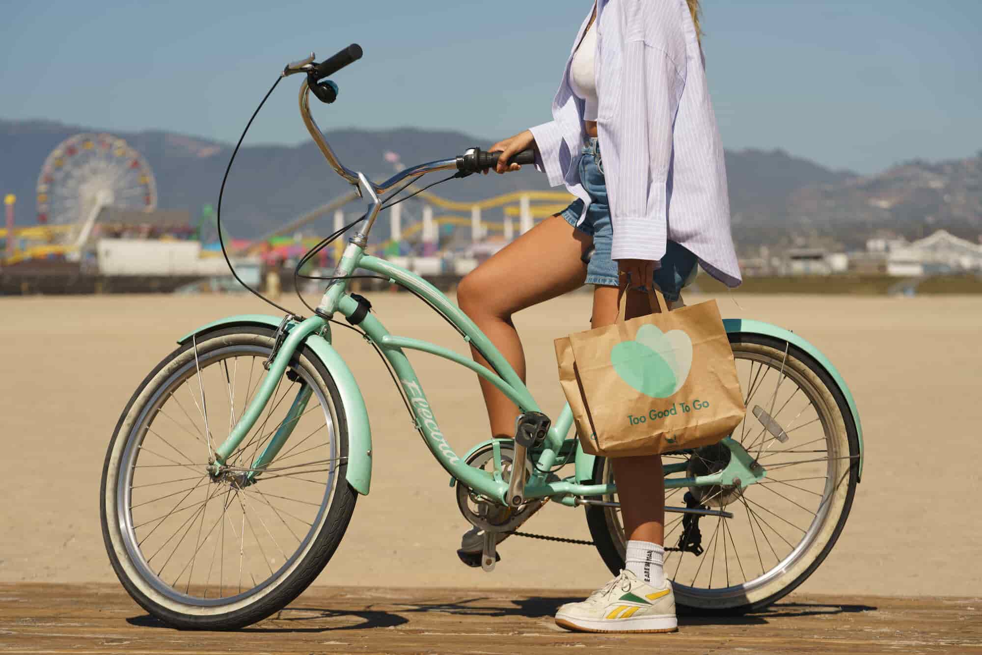 mujer en bicicleta con una bolsa de papel