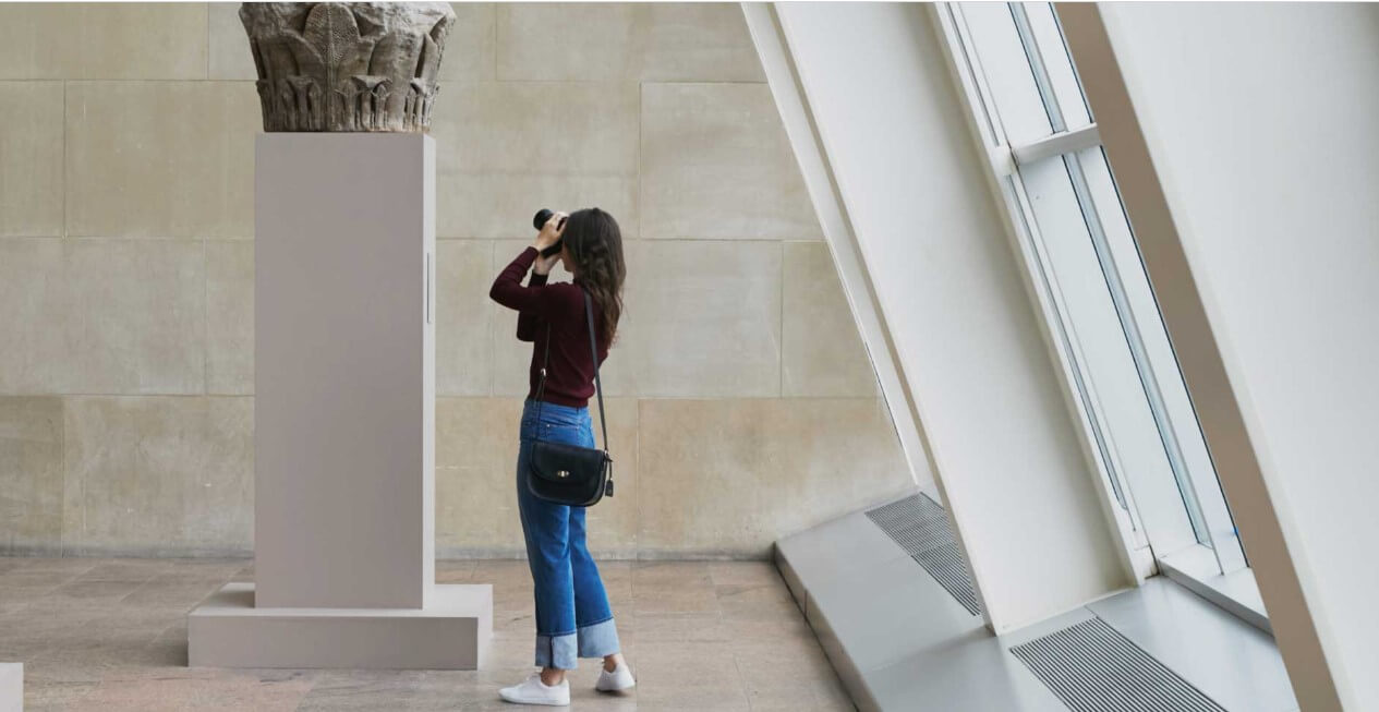 Mujer vistiendo Lo & Sons Bag mientras toma una foto en el museo
